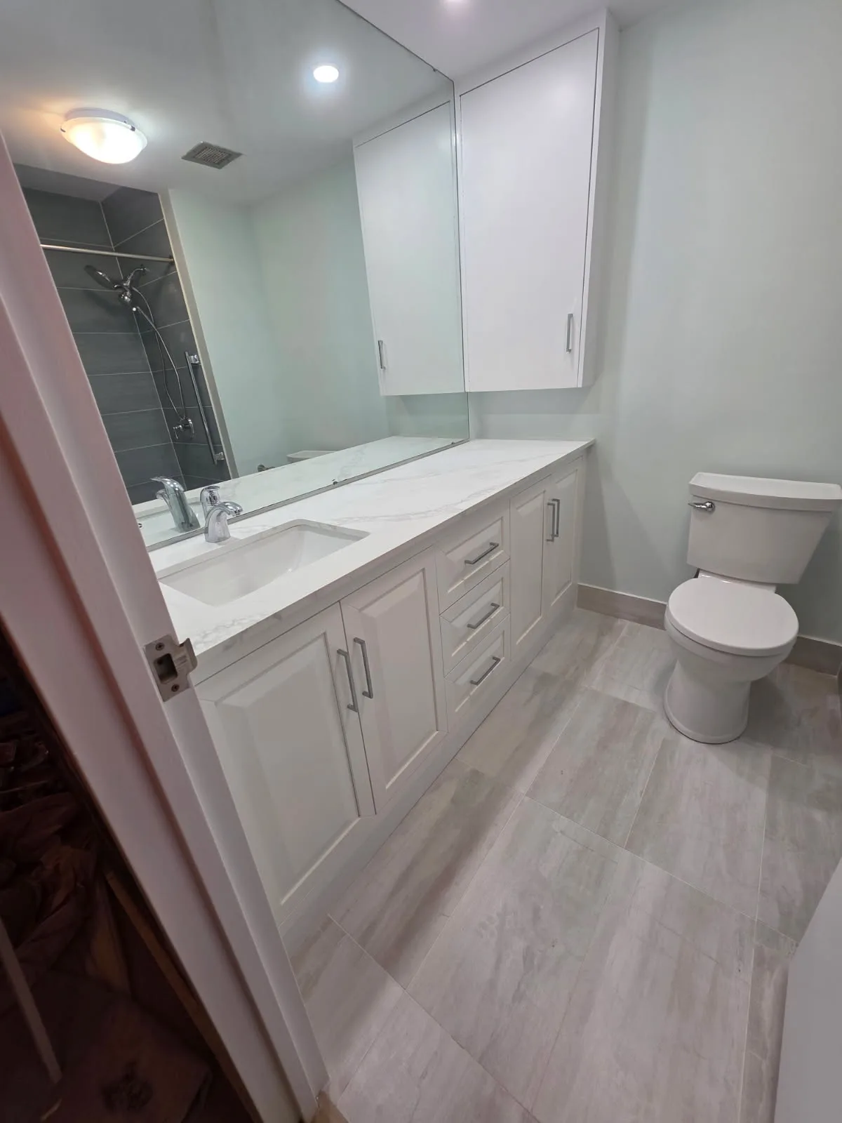 Finished modern bathroom with white shaker vanity, quartz countertop and new toilet